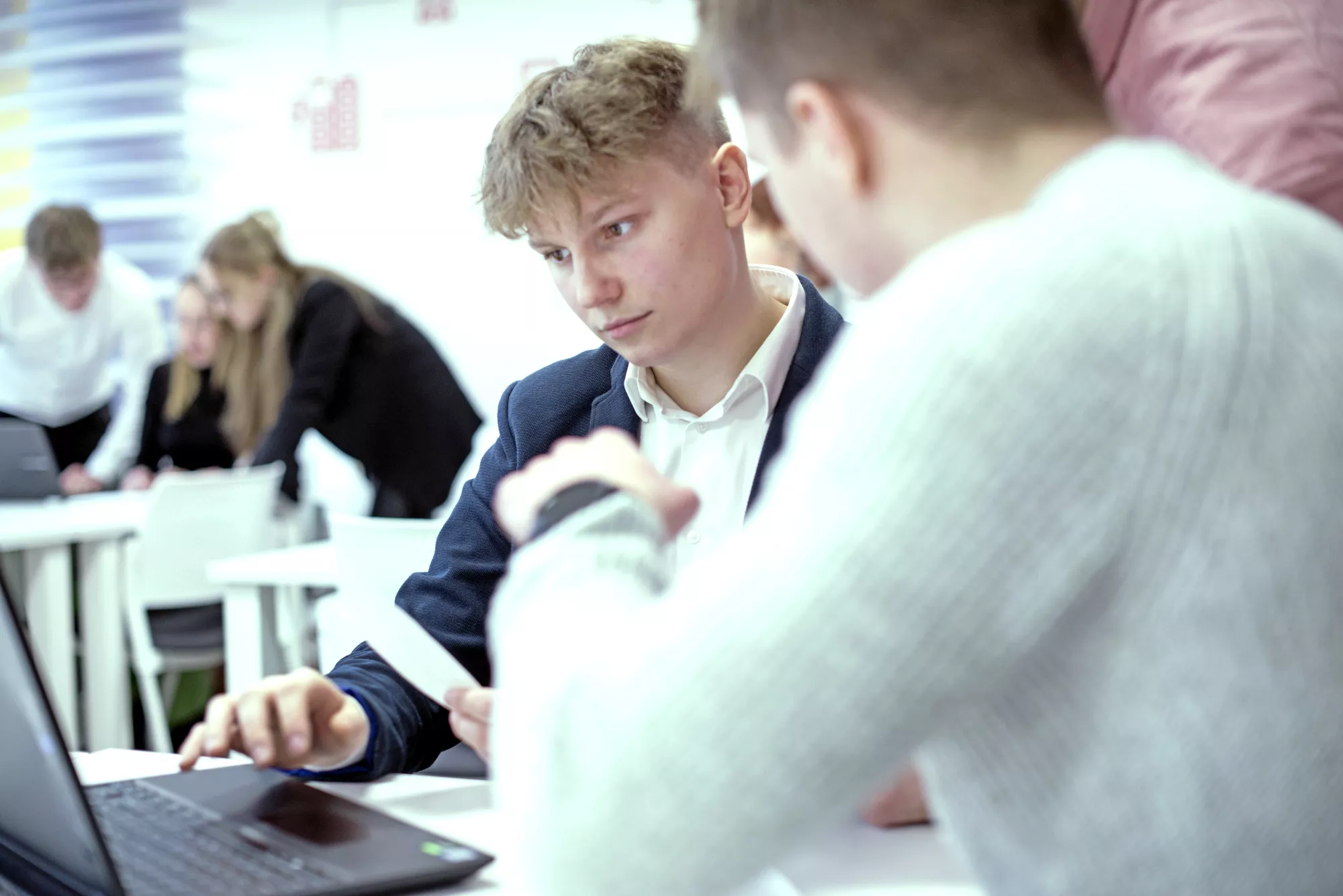 Studenci patrzą w laptop.